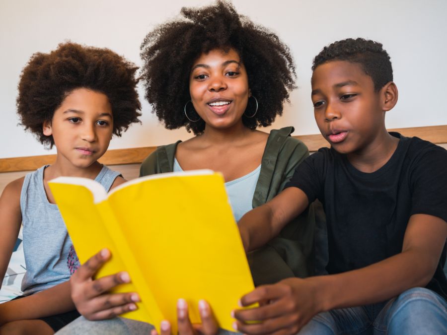 Mother and two sons reading a book together.