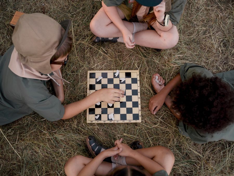 Four young friends by a board game in the grass.