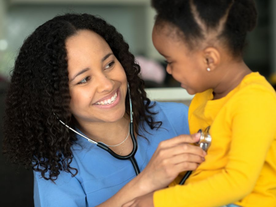 Nurse holding stethoscope to baby.
