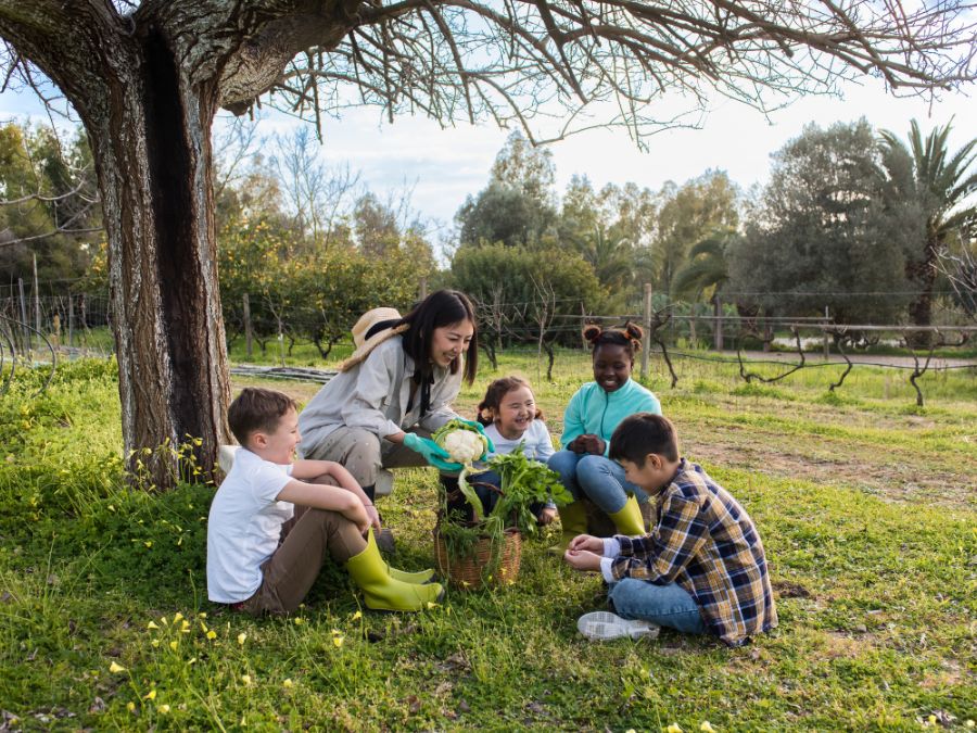 Children and teacher helping pot a plant.