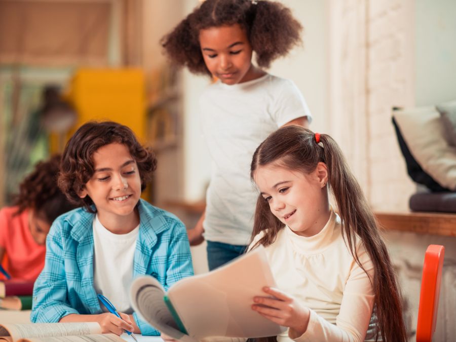 Three children looking at a packet together in a classroom.