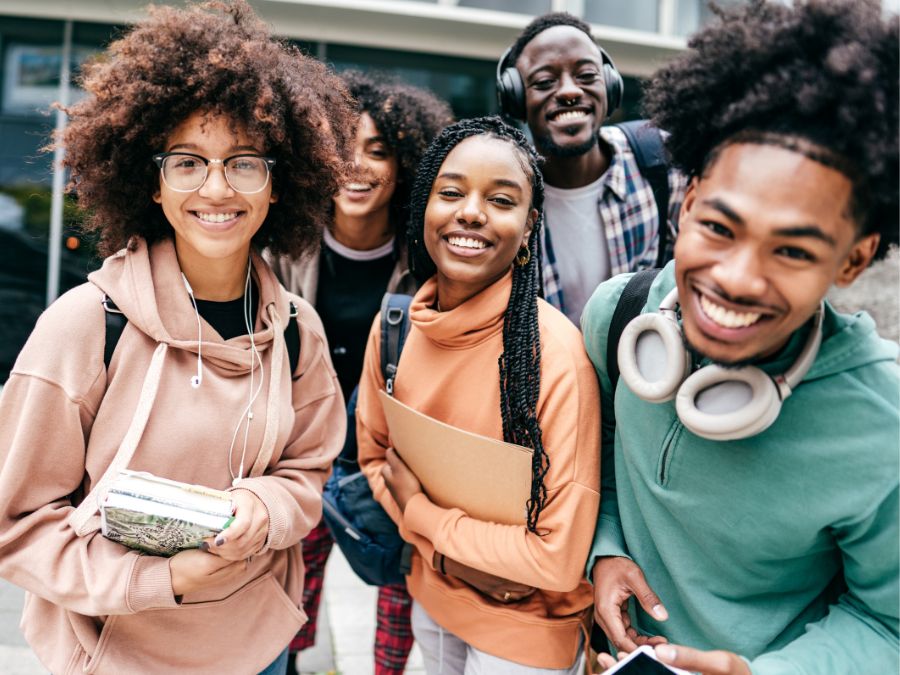 Five college friends smiling together.