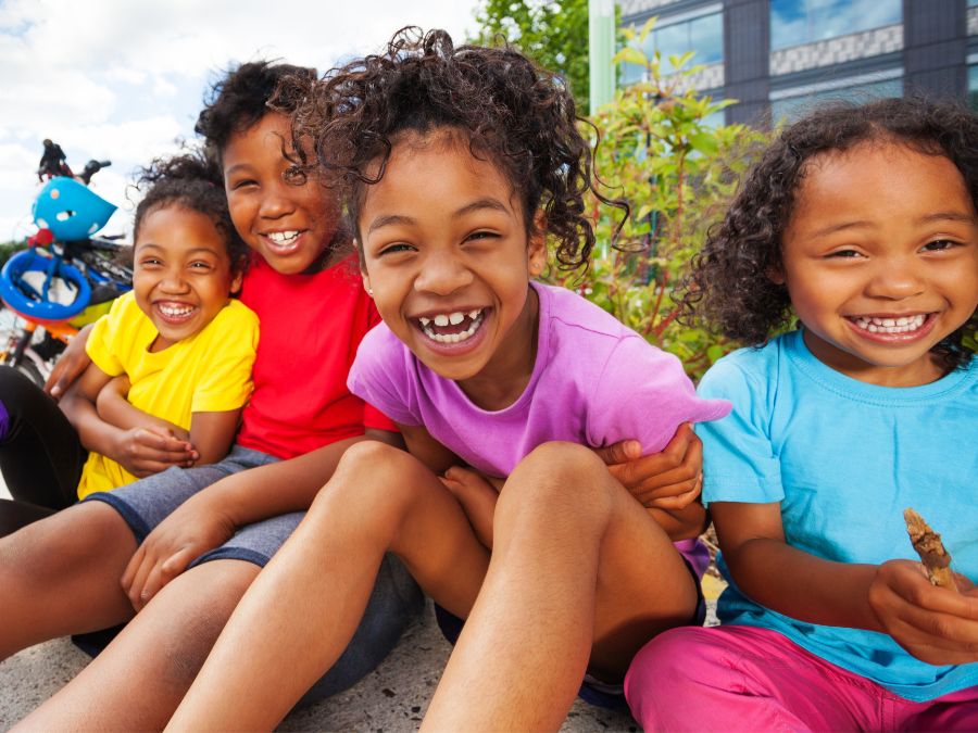 4 children sitting together laughing.