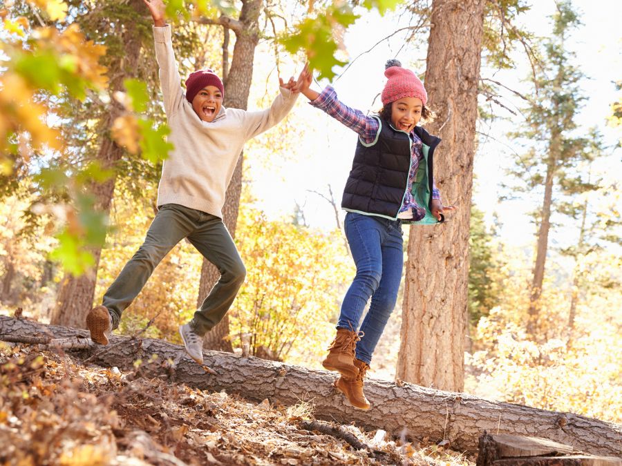 Two kids balancing on a log outside.