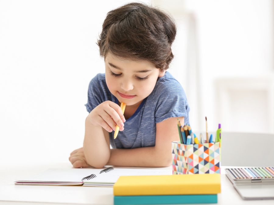 A child with a note book and pencil thinking.