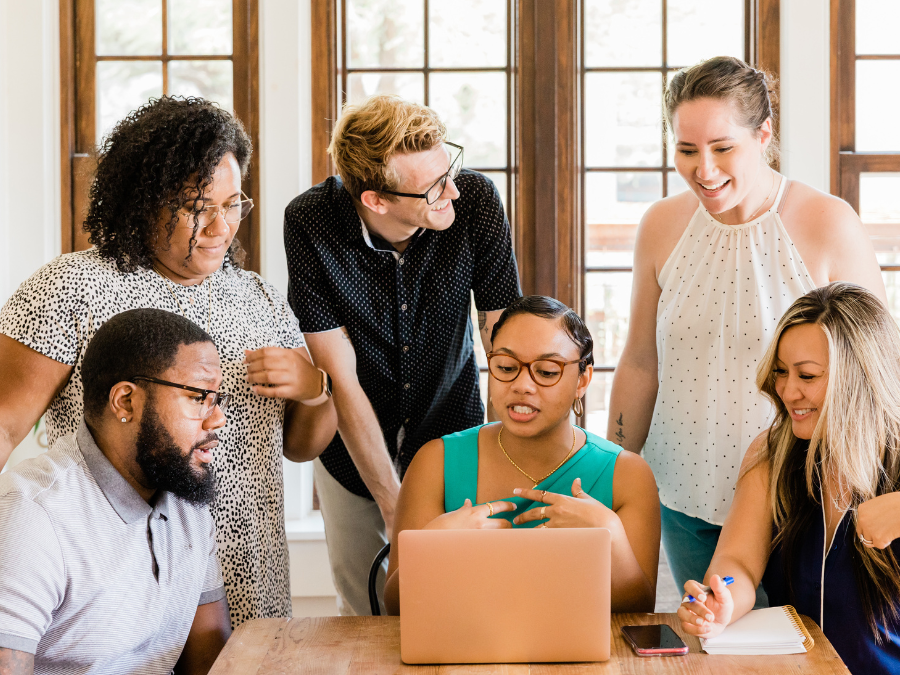 adults collaborating around a laptop