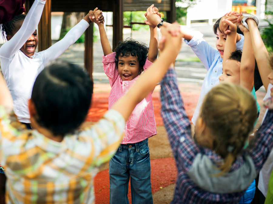 Group of children holding hands in the air.